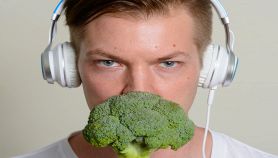 Uomo ascolta musica e annusa un broccolo