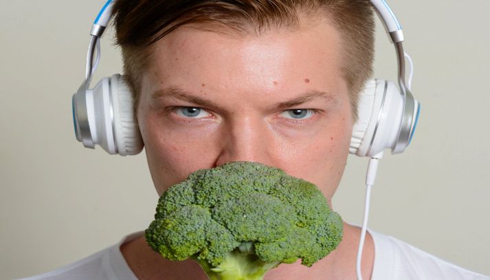 Uomo ascolta musica e annusa un broccolo