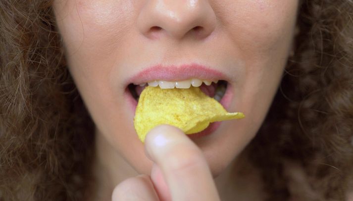 Bocca di donna che addenta una patatina croccante