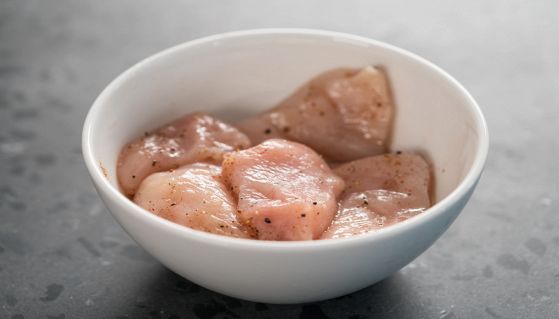 Carne di filetto di pollo affettata cruda con spezie e marinata in una ciotola