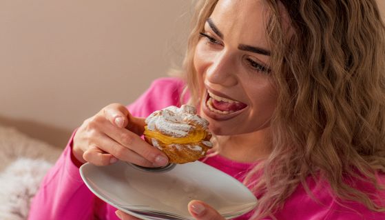 Donna sorridente mangia un gustoso bignè alla crema