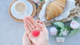 Mani ritagliate di donna che tiene a forma di cuore su sfondo blu