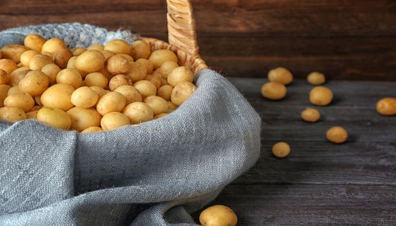 Cesto di vimini con patate appoggiato su un tavolo di legno