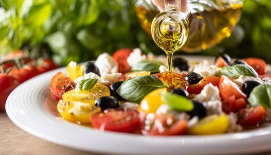 Un filo d'olio su un piatto di pomodori misti e olive nere