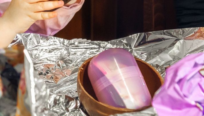 Una bambina apre un uovo di Pasqua contenente una sopresa