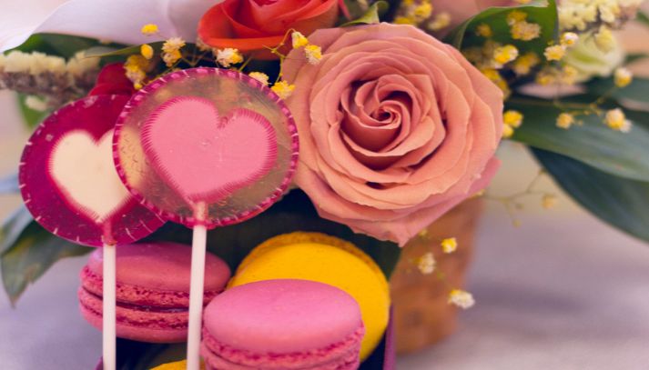 Composizioni festive romantiche con rose, macarons e caramelle
