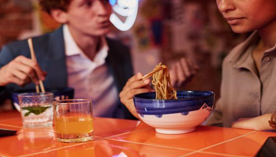 Coppia mangia noodles all'interno di un locale