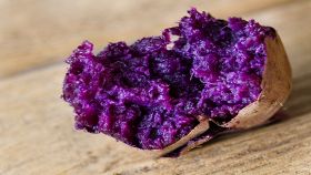 Patata viola arrosto su tavolo di legno