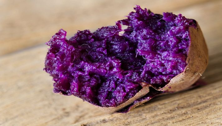 Patata viola arrosto su tavolo di legno