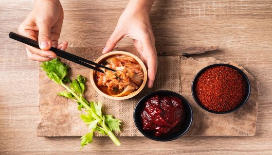 Persona gusta un delizioso kimchi con le bacchette insieme a una pasta di peperoncino rosso