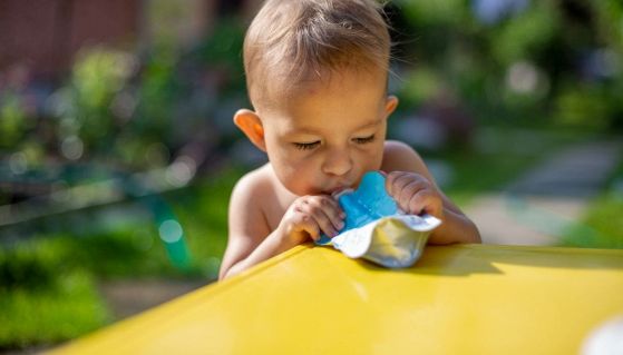 Un bambino mangia una purea di frutta in sacchetto squeeze