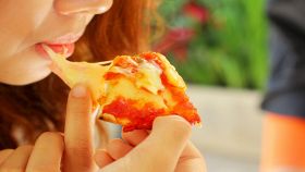 Ragazza mangia una gustosa e filante pizza margherita