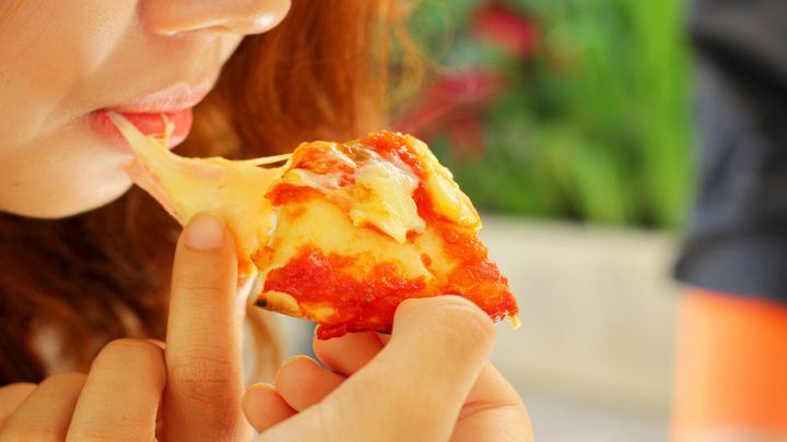 Ragazza mangia una gustosa e filante pizza margherita
