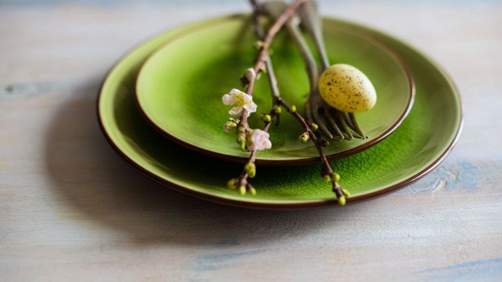 Un ramo di ciliegio in fiore come decorazione ornamentale su un piatto verde con uovo di quaglia