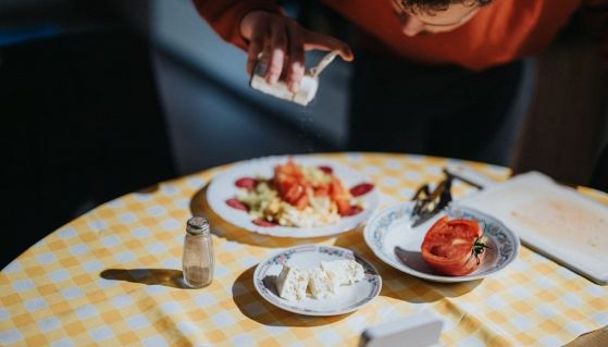 Un uomo versa del sale su un'insalata fredda al ristorante