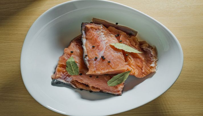 Salmone con alloro e pepe su piatto bianco