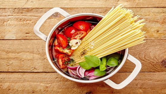 Spaghetti crudi in pentola con tutti gli ingredienti per il sugo