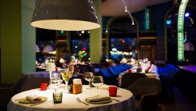 Tavolo con una tovaglia bianca, bicchieri, stoviglie e decorazioni in un ristorante buio