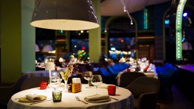 Tavolo con una tovaglia bianca, bicchieri, stoviglie e decorazioni in un ristorante buio