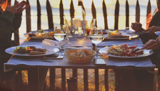 Tavolo di un ristorante vista mare con persone che cenano