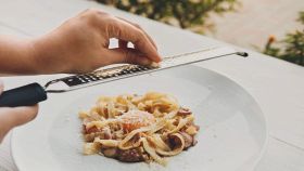 Chef donna grattugia il parmigiano sulla carbonara