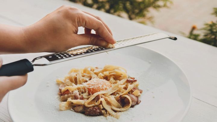 Chef donna grattugia il parmigiano sulla carbonara
