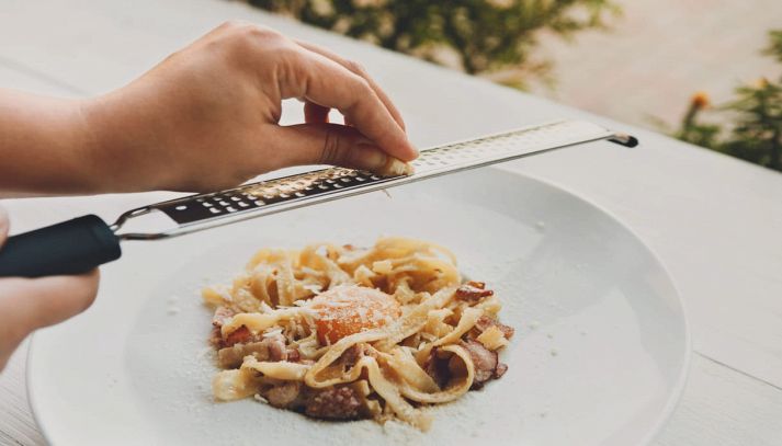 Chef donna grattugia il parmigiano sulla carbonara
