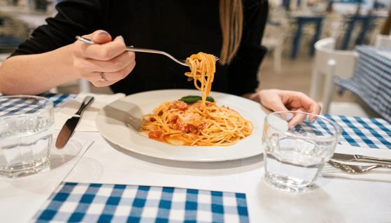 Ristorante con donna che mangia spaghetti al pomodoro