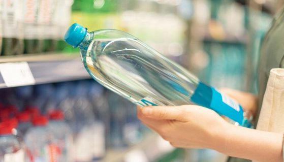 Donna al supermercato che tiene una bottiglia d'acqua