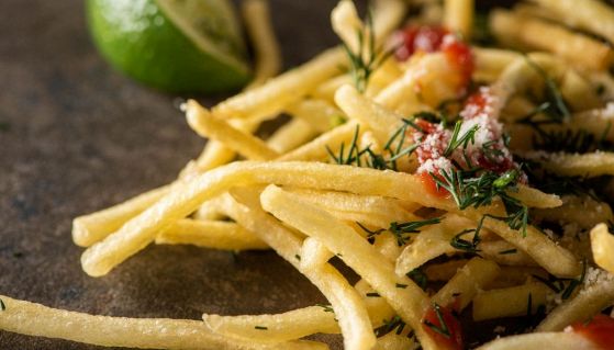 Patatine fritte condite con salsa di pomodoro, rosmarino, formaggio e lime
