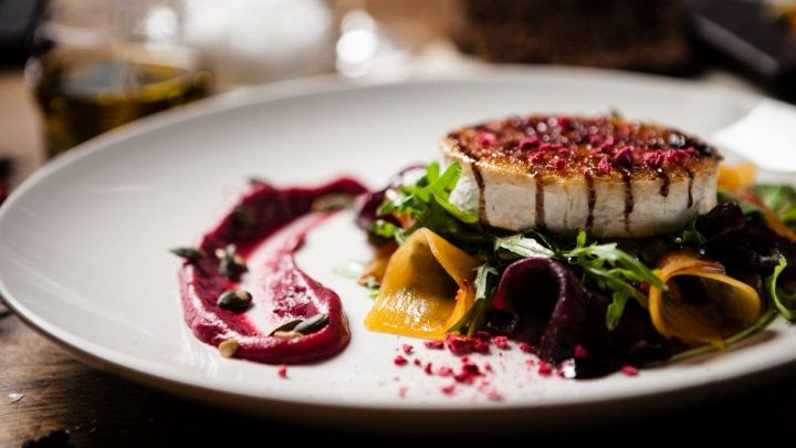 Piatto vegetariano di alta cucina a base di formaggio di capra con granella e crema di barbabietola