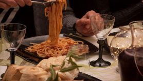 Persona serve spaghetti su tavolo imbandito