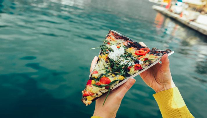 Spicchio di pizza farcita con mare sullo sfondo