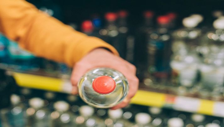 Uomo con bottiglia d'acqua al supermercato