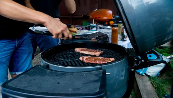 Uomo cuoce bistecche sul barbecue