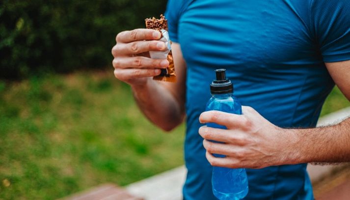 Un runner impugna una barretta proteica ed un energy drink