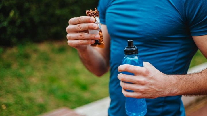 Un runner impugna una barretta proteica ed un energy drink