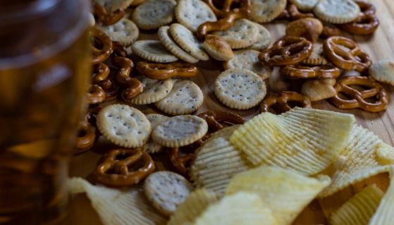 Una pinta di birra e snack salati di vario tipo disposti su un tavolo