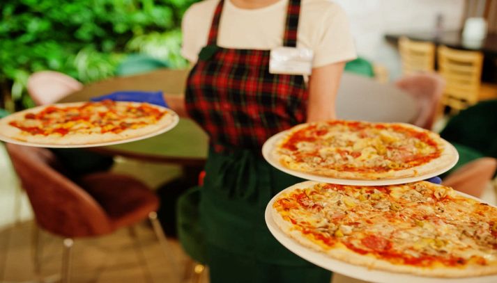 Cameriera del ristorante che porta le pizze