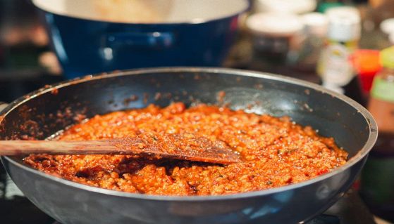 Ragù nella padella con il cucchiaio di legno