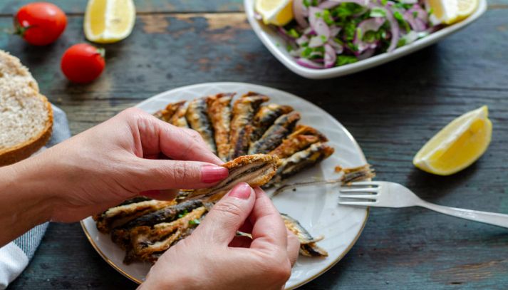 Alici fritte impiattate e mangiate da una donna