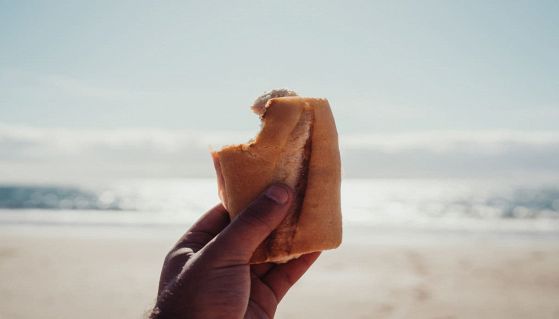 Mano che regge panino con mare sullo sfondo