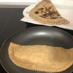 Padella con panino che cuoce e vassoio con panino già cotto