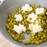 Piselli e ricotta di capra nella pentola con cucchiaio di legno