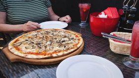 Donna al ristorante con una pizza appena sfornata