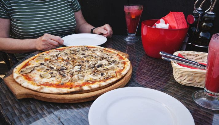 Donna al ristorante con una pizza appena sfornata