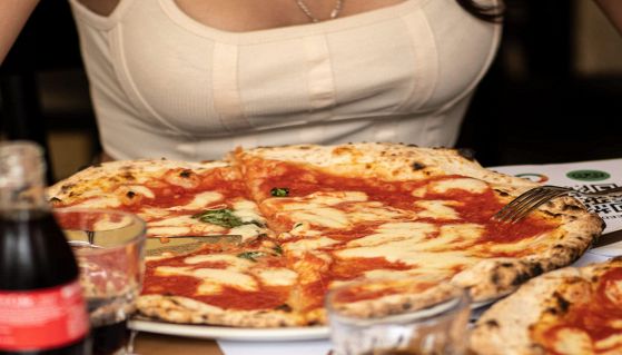 Ragazza mangia una pizza al ristorante