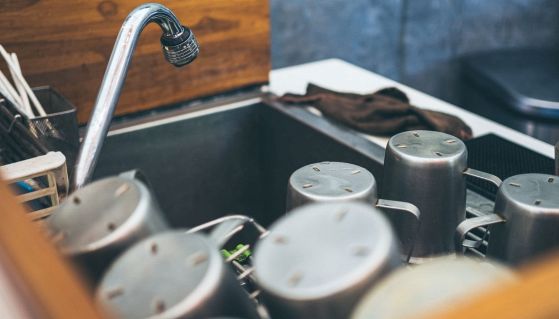 Rubinetto nella cucina di un bar con tazze di alluminio ad asciugare