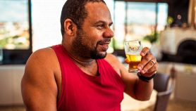 Uomo in canottiera rossa beve una birra in un ristorante