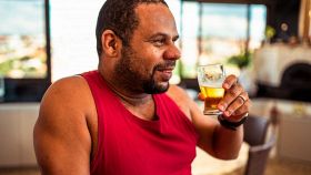 Uomo in canottiera rossa beve una birra in un ristorante